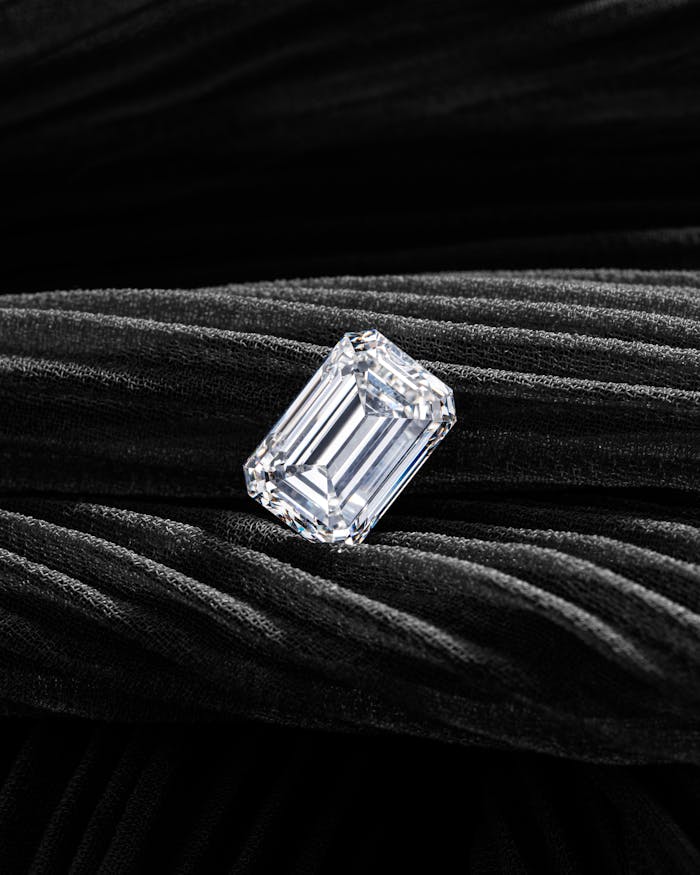 A radiant emerald-cut diamond showcased on a textured black velvet background, exuding elegance and luxury.